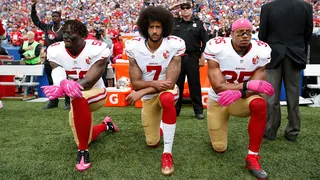 Colin Kaepernick kneeling with Eli Harold and Eric Reid on the sideline during the anthem