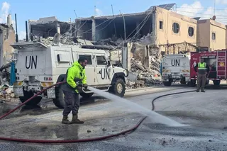 United Nations peacekeepers with the UN Interim Force in Lebanon (UNIFIL) drive past firefighters clearing the road at the site of an overnight Israeli air strike in southern Lebanon in March. Photo: AFP