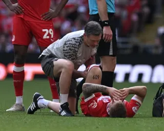 A medical staff member kneels beside injured player Riley McGree lying on the pitch at Wembley