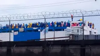 Briceida Morales / AFP via Getty Images Venezuelan prisoners gather in protest on the roof of the Judicial Detention Centre in Barinas, Venezuela on 24 May, 2026. The inmates are wearing jumpsuits, some of them yellow, others blue. They have hung hand-drawn signs from the roof.