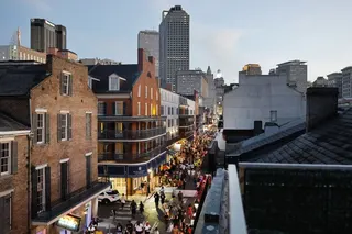 People walk on Bourbon Street in the French Quarter with the downtown skyline beyond on August 8, 2025 in New Orleans, Louisiana.