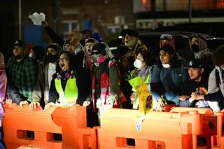 Protesters stand behind orange barriers outside Delaney Hall immigration detention center at night