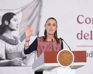 Woman stands at podium with one hand raised