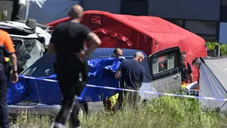 Staff cover a hearse parked next to the crashed bus at the site of an accident after a train crashed into a school bus, at the railway crossing Vierhuizen in Buggenhout, some 20kms north of Brussels