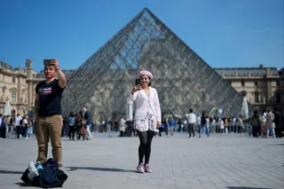 Tourists take selfies in front of the glass pyramid of the Louvre museum in Paris, France, in April. Photo: RReuters