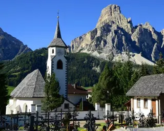 Corvara, showing church against mountains with blue sky
