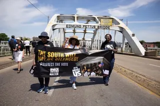 people hold a banner that reads 'the south will not be silenced' while walking across a bridge