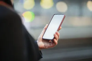 Close-Up of Person Holding Smartphone with Blurred City Lights in Background
