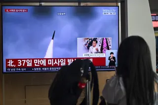 A woman watches a television screen showing a news broadcast with file footage of a North Korean missile test, at a train station in Seoul May 26, 2026. — AFP pic