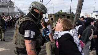 A woman shouts at an ICE agent outside the facility.