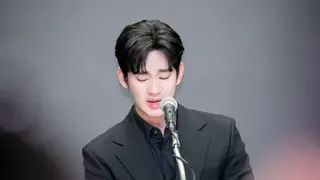 iMBC/Imazins via Getty Images A tearful Kim Soo-hyun speaking into a microphone. He is wearing a fully black outfit.