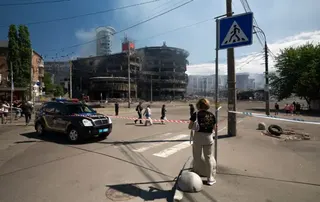 在基輔，人們走過一棟嚴重受損的建築物，警察也在現場。