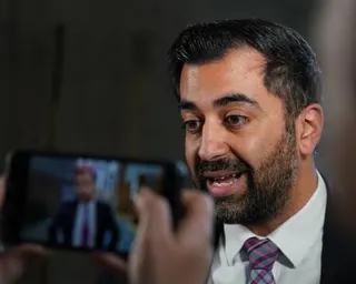 Humza Yousaf in a suit and patterned tie speaks while being filmed on a phone