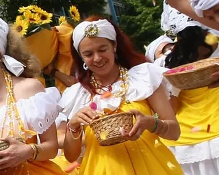 Daniela Klette takes part in a parade dressing in a yellow dress and white bandana and carrying a small basket of petal confetti