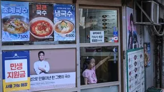 周一在韩国首尔一家餐厅里，一名小女孩在窗边做手势。（图取自法新社）