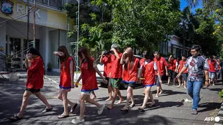 5月8日，印尼警方在泗水就一起网络诈骗案举行记者会之前，押送了一群来自中国、日本和台湾的嫌犯。（图取自法新社）