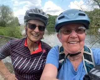 Mary Ann Hooper and a friend in cycling helmets smile for the camera