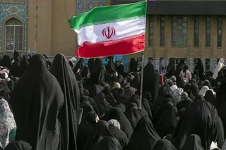 A woman is seen holding an Iranian flag during a religious ceremony during Eid al-Adha in Qom, Iran on May 26.