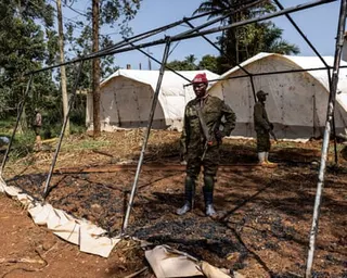 Congolese soldiers stand inside burned frame of tent