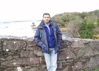 Tahir standing next to a wall with a sea view behind him.