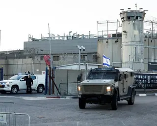 Vehicles outside grey prison walls.