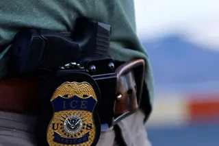 The badge of a U.S. Immigration and Customs Enforcement (ICE) agent is seen during an operation with migrants being transferred to a plane to be expelled under US