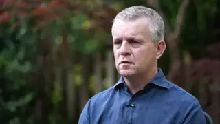 David Parfett speaking during an interview being conducted outdoors. He has short, grey hair and is wearing a blue shirt. Trees and leaves are in the background.