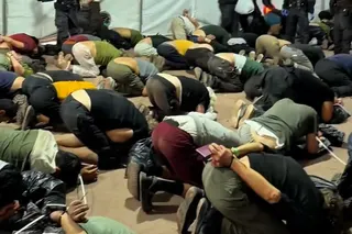 People are seen shackled and kneeling on the ground.