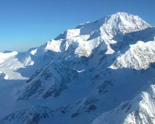 Completely snowy mountain top on a clear day.