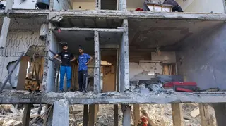Palestinians inspect the site of an Israeli strike on a house
