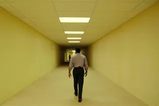 Clark (Chiwetel Ejiofor) walks through a long hallway with yellow walls, floor, and ceiling panels in Backrooms