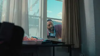 Clark (Chiwetel Ejiofor) peers through the curtained window of a house in Backrooms