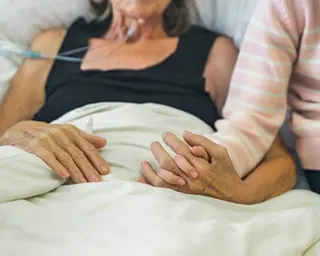 Young girl holds the hand of her ill grandmother