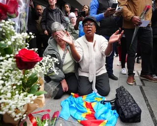 Antoinette Lukeba holds her hands aloft beside flowers at a vigil for Yves Sakila on Henry Street, Dublin.