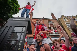 Arsenal fans celebrate as they wait for the buses to pass by carrying the team during a parade for winning the English Premier League title, in London on Sunday. Photo: AP