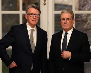 Starmer and Mandelson in dark suits stand side by side in front of windows