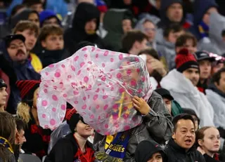 Sports fans at a stadium try to shelter from a storm