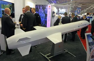 Visitors are gathered next to a display of an NSM Naval Strike Missile made by Norwegian company Kongsberg, presented at the Euronaval show, in Le Bourget, North of Paris, France, Wednesday Oct. 29, 2014. (AP Photo/Remy de la Mauviniere)