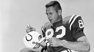 David Driscoll, 9, wearing Baltimore Colts uniform, getting autograph from Raymond Berry at training camp