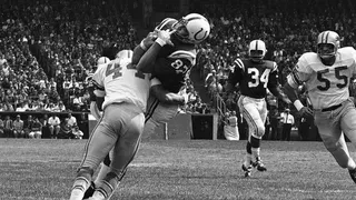 Baltimore Colts end Raymond Berry catching a pass from quarterback John Unitas during a football game.