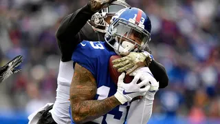Odell Beckham Jr. catching football under pressure from Isaiah Johnson during game.