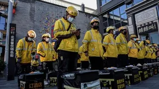2021年10月19日，在中国北京，美团外卖员在街头列队准备开始送餐。 （图取自法新社）