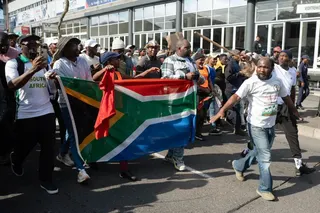 Demonstrators hold a South African flag as they march.