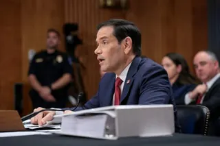 a man speaks into a microphone while seated at a table