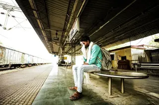 在班達一個廢棄的火車站台上，一名男子坐著，用一塊白布擦拭額頭。