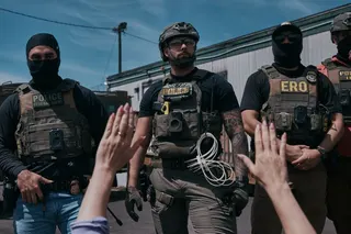 A protester holds her hands up at ICE agents.