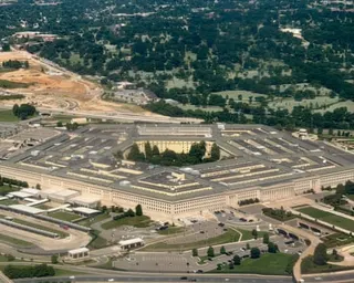An aerial view of the Pentagon in Arlington showing its distinctive five-sided structure surrounded by parking lots and highways.