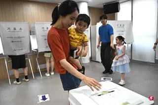 一名母亲在首尔的投票站投票。 （法新社）