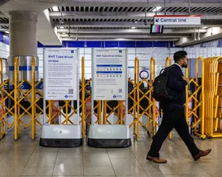 A man in a suit walks past yellow barriers and signs about tube strikes at a station entrance