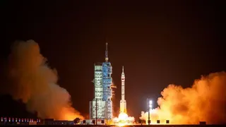 夜幕降臨，火箭從發射台上發射升空，周圍燃起熊熊火焰，濃煙滾滾。